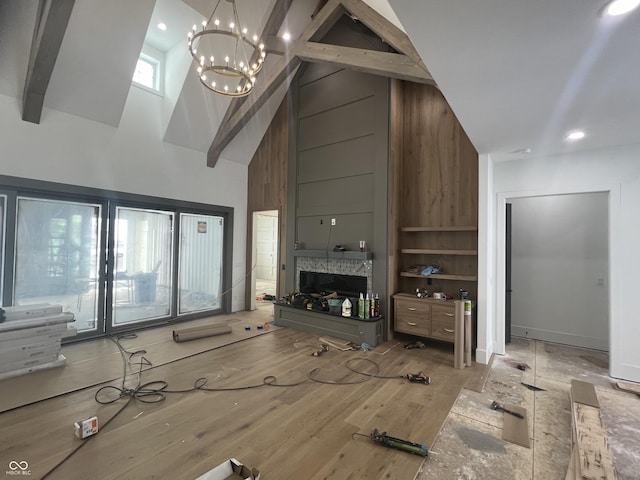 living room with beamed ceiling, high vaulted ceiling, an inviting chandelier, and light hardwood / wood-style floors