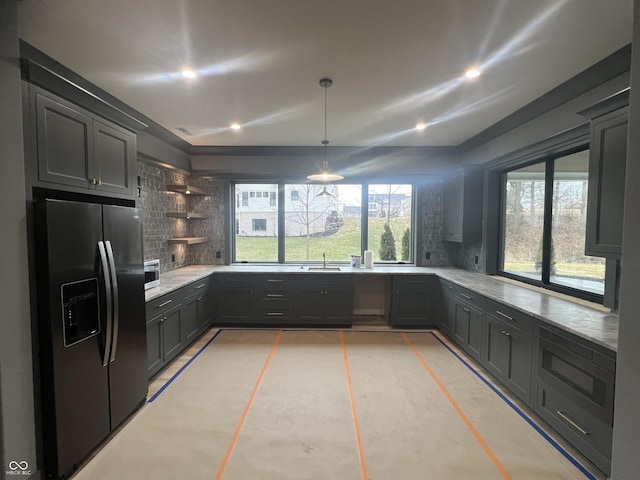 kitchen with sink, fridge with ice dispenser, decorative light fixtures, stainless steel microwave, and decorative backsplash