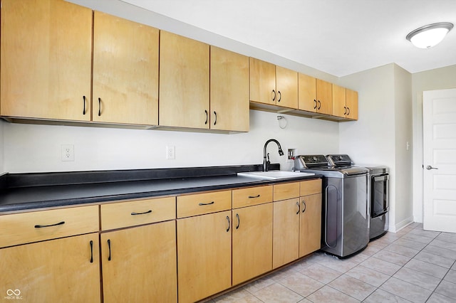 kitchen featuring sink, light tile patterned flooring, washing machine and clothes dryer, and light brown cabinets