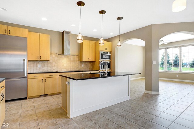 kitchen featuring appliances with stainless steel finishes, ceiling fan, wall chimney exhaust hood, and light brown cabinets