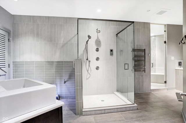 bathroom featuring vanity, walk in shower, and tile walls