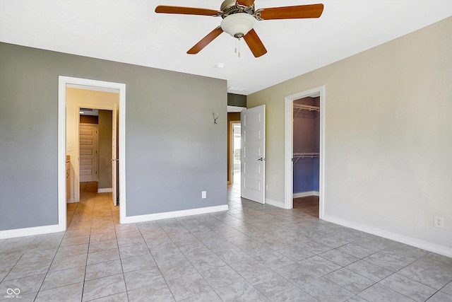 unfurnished bedroom with a walk in closet, ceiling fan, light tile patterned floors, and a closet