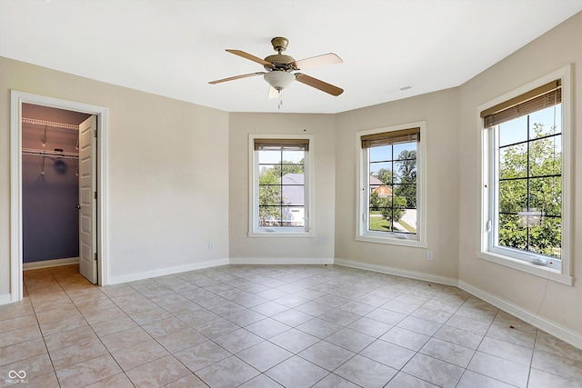 tiled spare room featuring ceiling fan and a healthy amount of sunlight