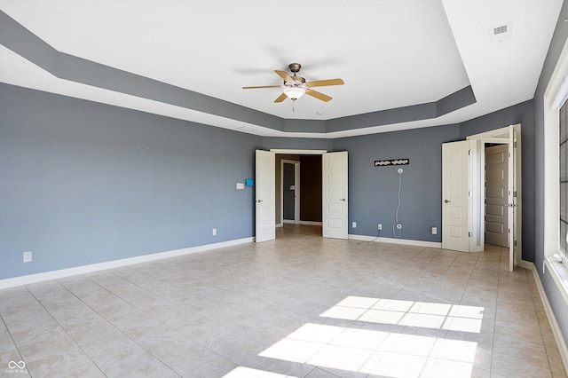 unfurnished bedroom with a raised ceiling, light tile patterned flooring, and ceiling fan