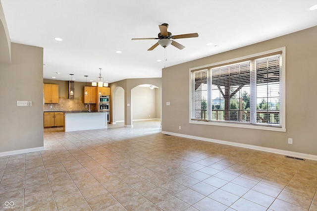 unfurnished living room with sink, ceiling fan, and light tile patterned floors