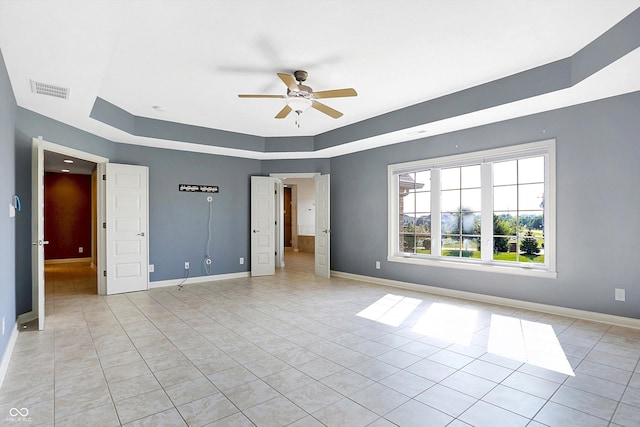 unfurnished bedroom featuring light tile patterned flooring, ceiling fan, and a tray ceiling