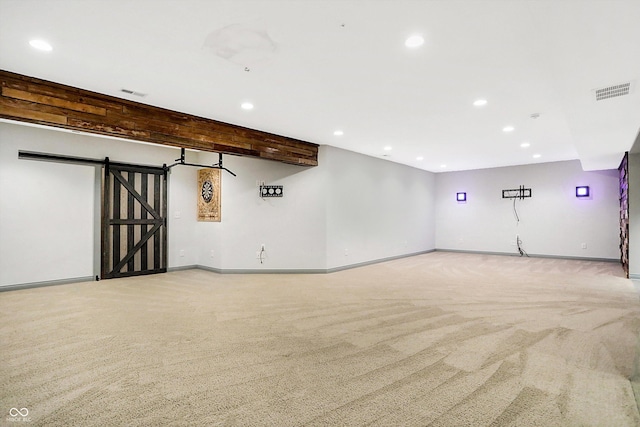 empty room featuring beamed ceiling, a barn door, and light colored carpet