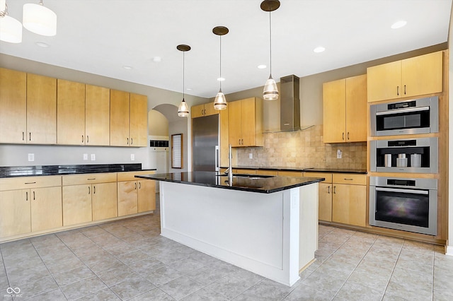 kitchen with a kitchen island with sink, hanging light fixtures, light brown cabinets, sink, and wall chimney range hood