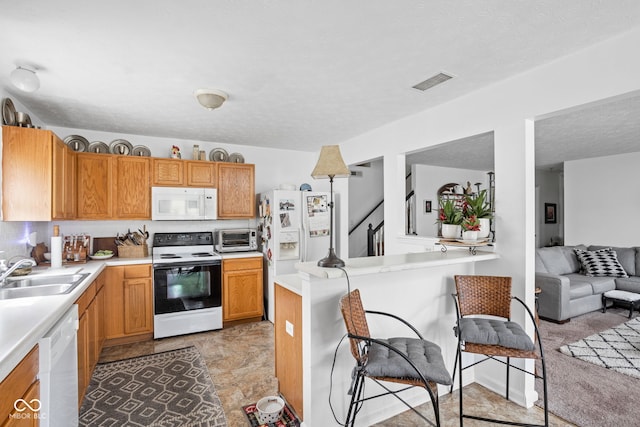 kitchen featuring white appliances, visible vents, a sink, light countertops, and a textured ceiling