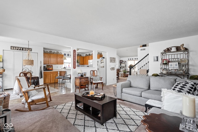 living room with light carpet, a textured ceiling, and stairs