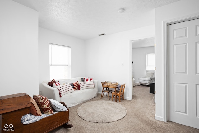 carpeted living room featuring visible vents, baseboards, and a textured ceiling