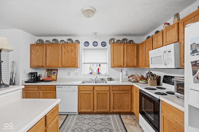 kitchen featuring a sink, white appliances, a textured ceiling, and light countertops