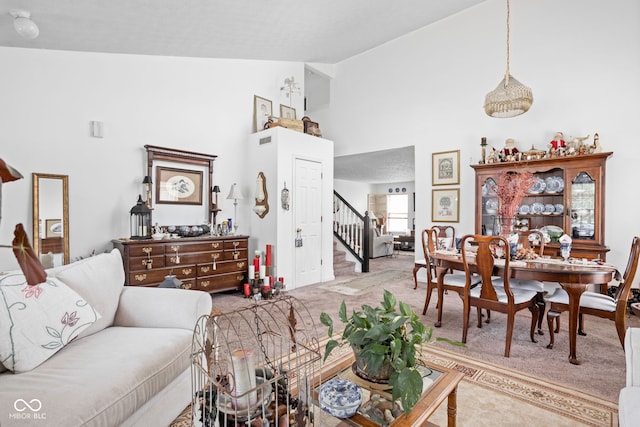 carpeted living area featuring stairway and high vaulted ceiling