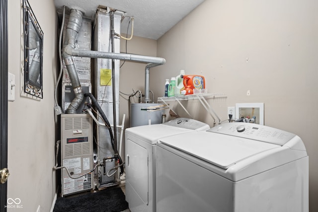 laundry area featuring water heater, laundry area, washing machine and dryer, and a textured ceiling