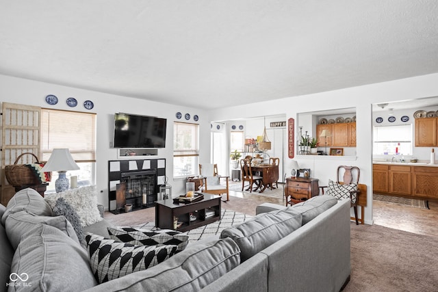 living area featuring a glass covered fireplace, a wealth of natural light, and light carpet