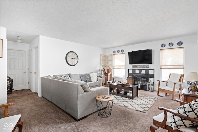 living area featuring a glass covered fireplace, a textured ceiling, and carpet