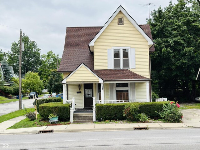 traditional-style home with covered porch and a shingled roof