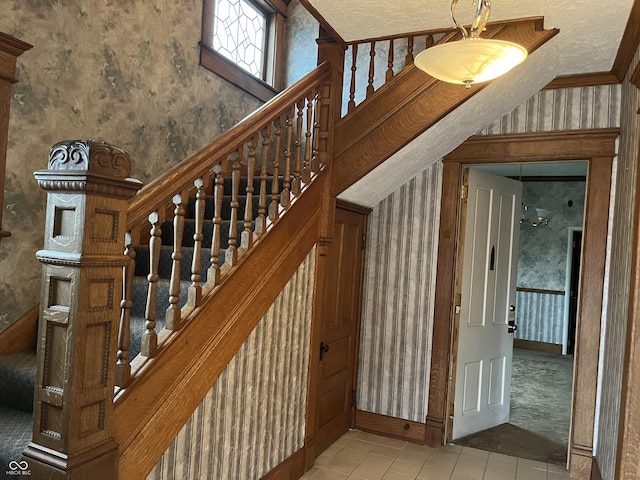 stairway with baseboards, tile patterned floors, and wallpapered walls