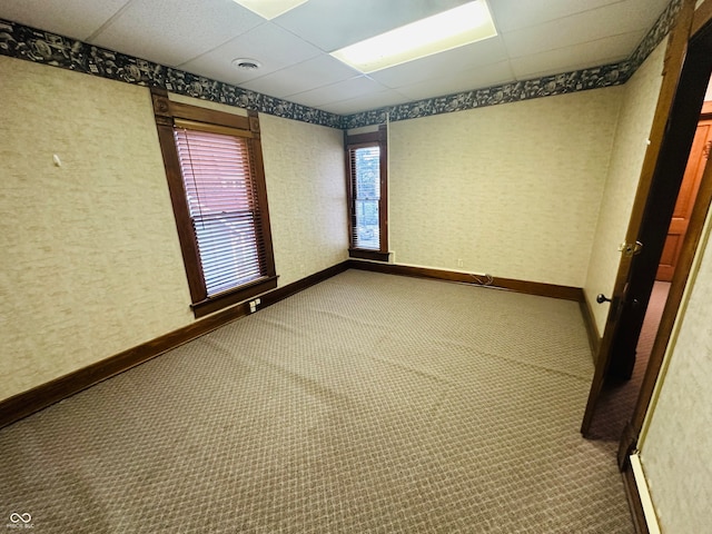 carpeted empty room with a drop ceiling