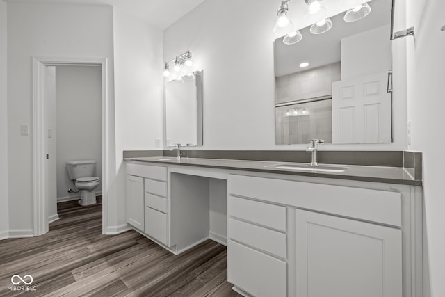 bathroom with toilet, vanity, hardwood / wood-style floors, and a shower with door