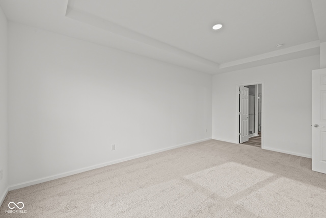 unfurnished room featuring carpet and a raised ceiling