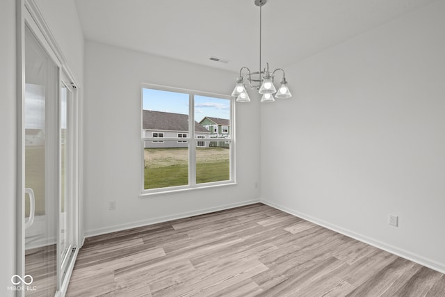 unfurnished dining area with light hardwood / wood-style floors and a chandelier