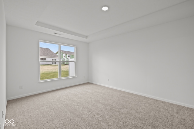 carpeted empty room featuring a tray ceiling