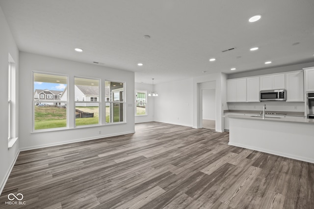 unfurnished living room featuring hardwood / wood-style flooring, plenty of natural light, a notable chandelier, and sink