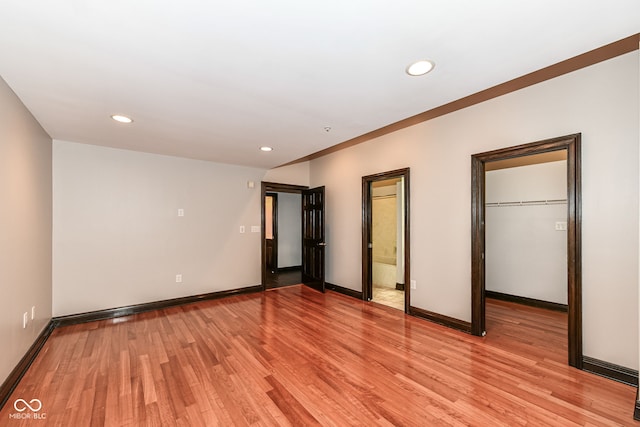 unfurnished bedroom with light hardwood / wood-style floors, a spacious closet, and a closet