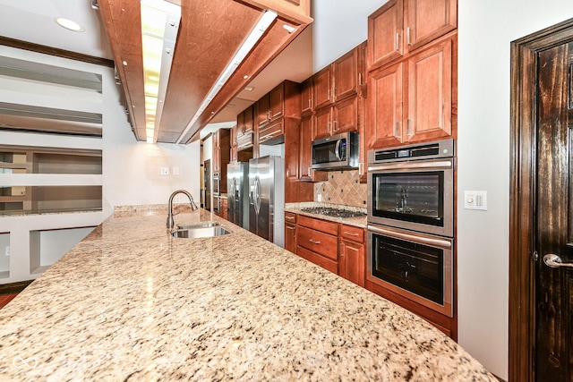 kitchen featuring backsplash, light stone countertops, sink, and stainless steel appliances