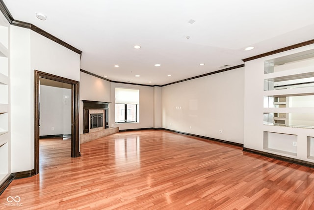 unfurnished living room featuring a fireplace, light hardwood / wood-style floors, and crown molding