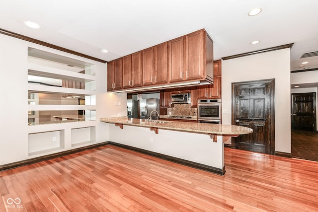 kitchen with a kitchen breakfast bar, kitchen peninsula, stainless steel appliances, and tasteful backsplash