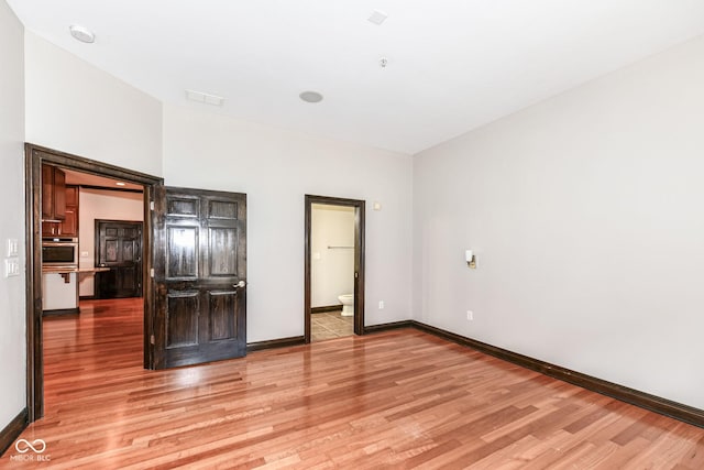 unfurnished bedroom featuring light hardwood / wood-style flooring and ensuite bath