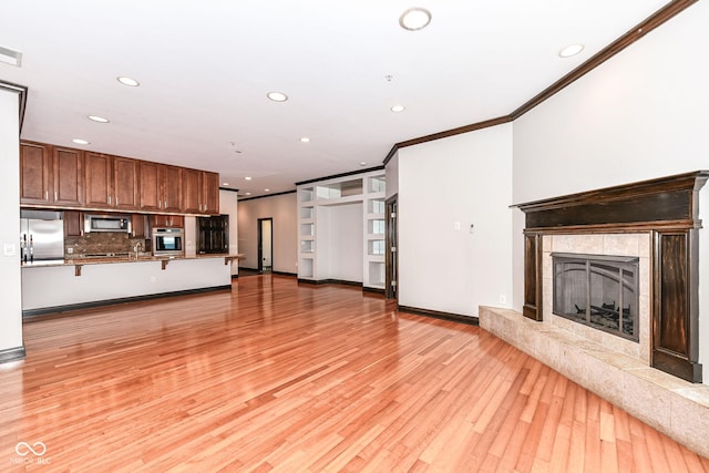 unfurnished living room featuring crown molding, a high end fireplace, and light hardwood / wood-style flooring