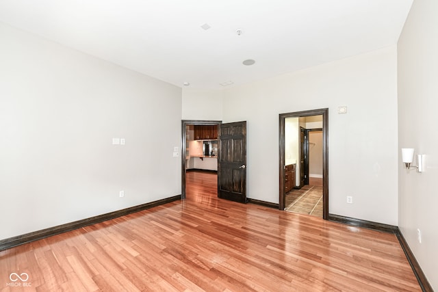 unfurnished bedroom featuring ensuite bathroom and light hardwood / wood-style floors