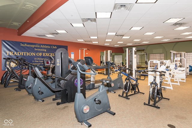 gym with a paneled ceiling and light colored carpet