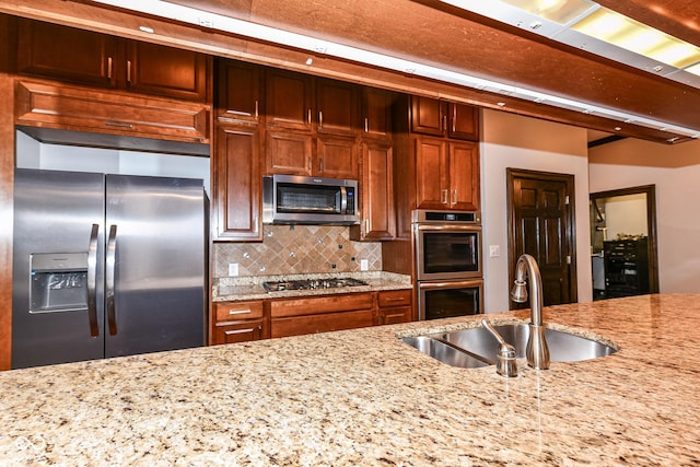 kitchen featuring backsplash, sink, light stone countertops, and stainless steel appliances