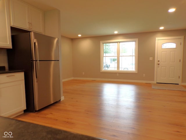 kitchen with white cabinetry, stainless steel fridge, and light hardwood / wood-style flooring