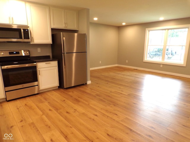 kitchen with light hardwood / wood-style floors, white cabinets, and appliances with stainless steel finishes