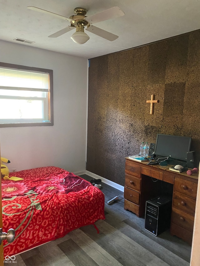 bedroom with ceiling fan, dark hardwood / wood-style floors, and wooden walls