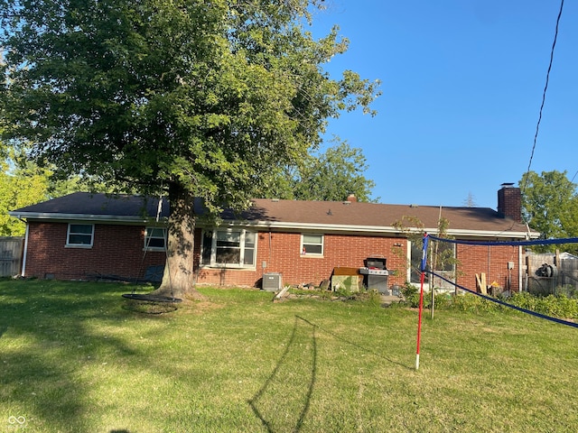 rear view of property featuring a lawn and central AC