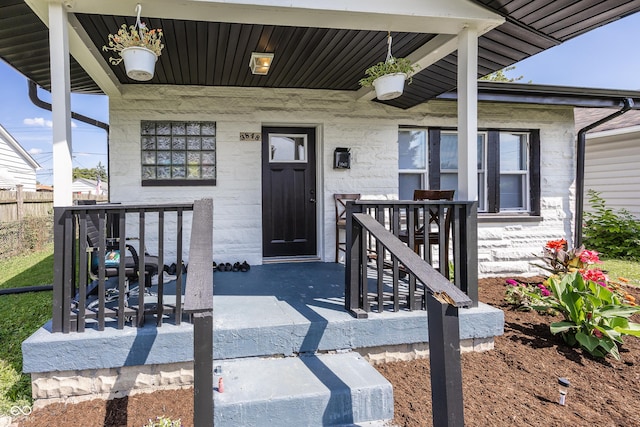 property entrance featuring covered porch and fence