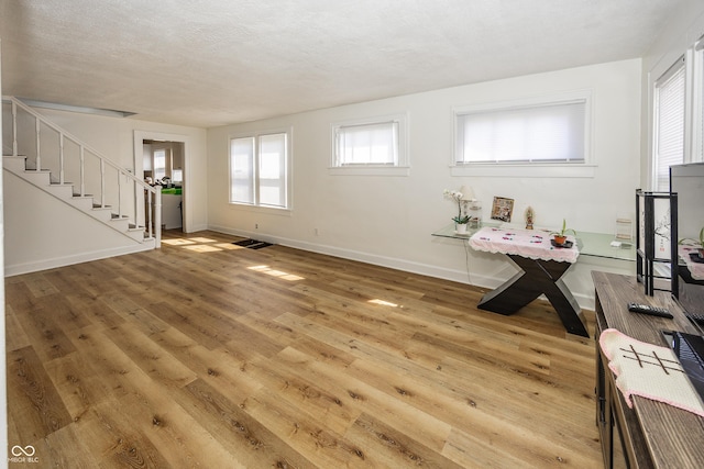 interior space with a textured ceiling, stairway, baseboards, and wood finished floors