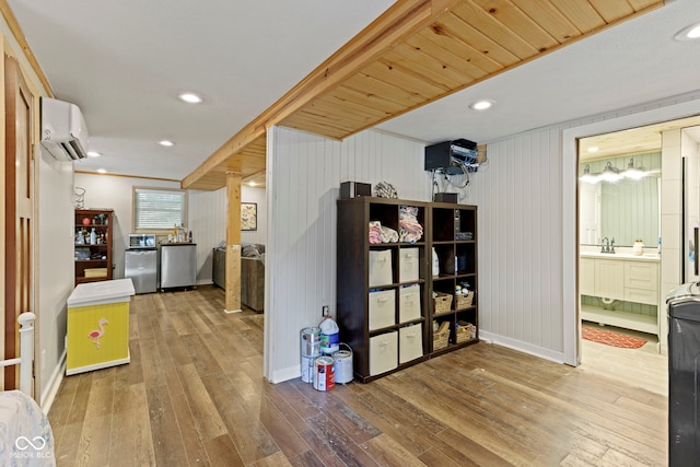 interior space featuring recessed lighting, wood-type flooring, baseboards, and a wall mounted air conditioner