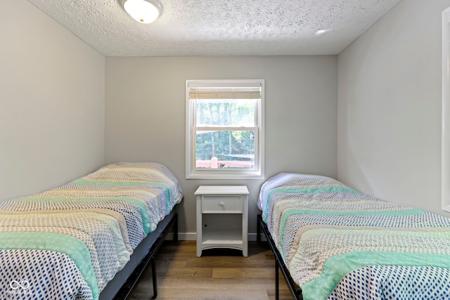 bedroom with a textured ceiling, wood finished floors, and baseboards