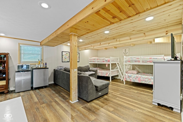 bedroom featuring stainless steel refrigerator, wood finished floors, refrigerator, beam ceiling, and recessed lighting