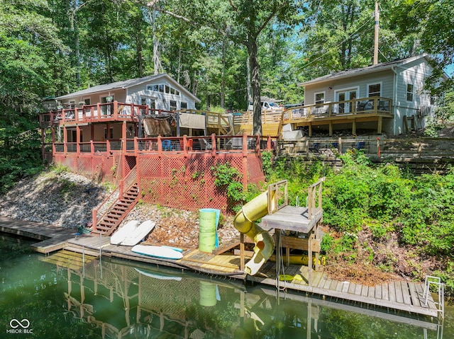 back of property with stairs and a deck with water view