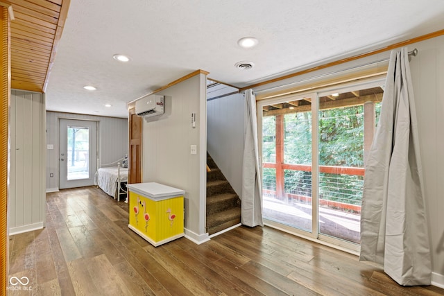 interior space featuring visible vents, hardwood / wood-style floors, a wall mounted air conditioner, baseboards, and stairs