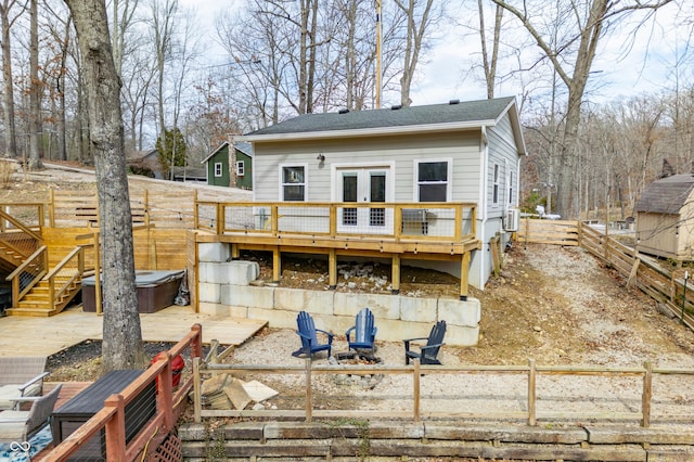 back of house featuring a deck, an outdoor fire pit, a fenced backyard, stairs, and a hot tub