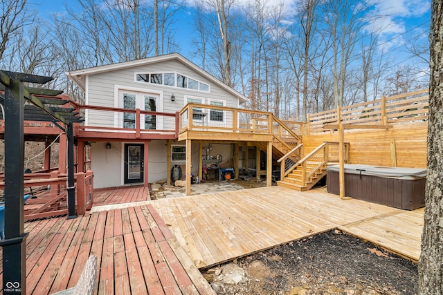 rear view of house featuring a deck, fence, stairs, and a hot tub